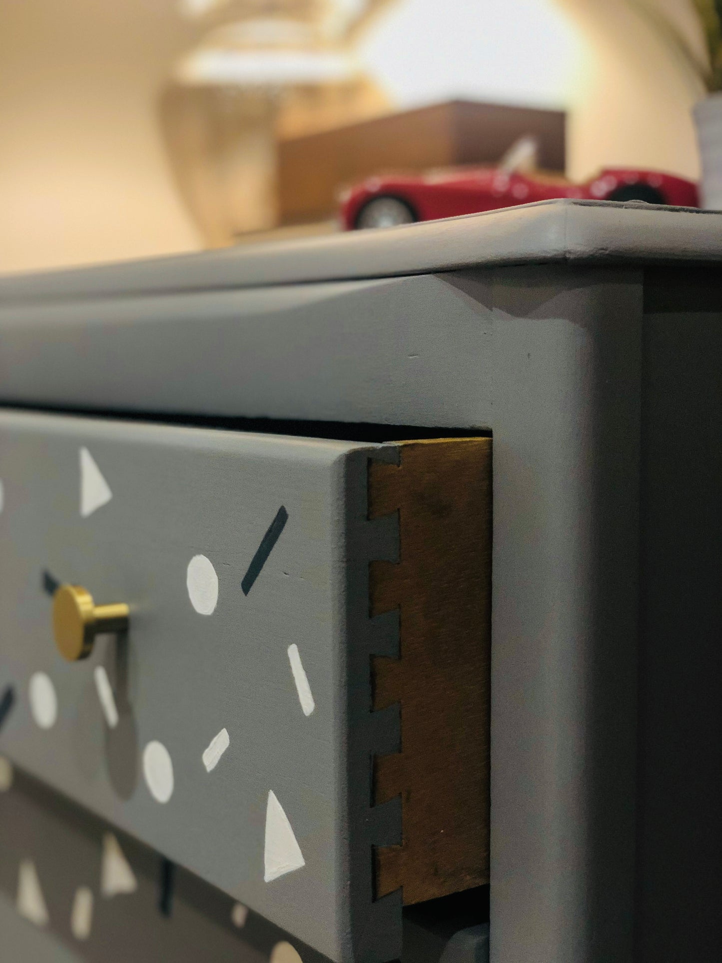 Small Harris Lebus chest of drawers in grey with small shapes painted on the drawers