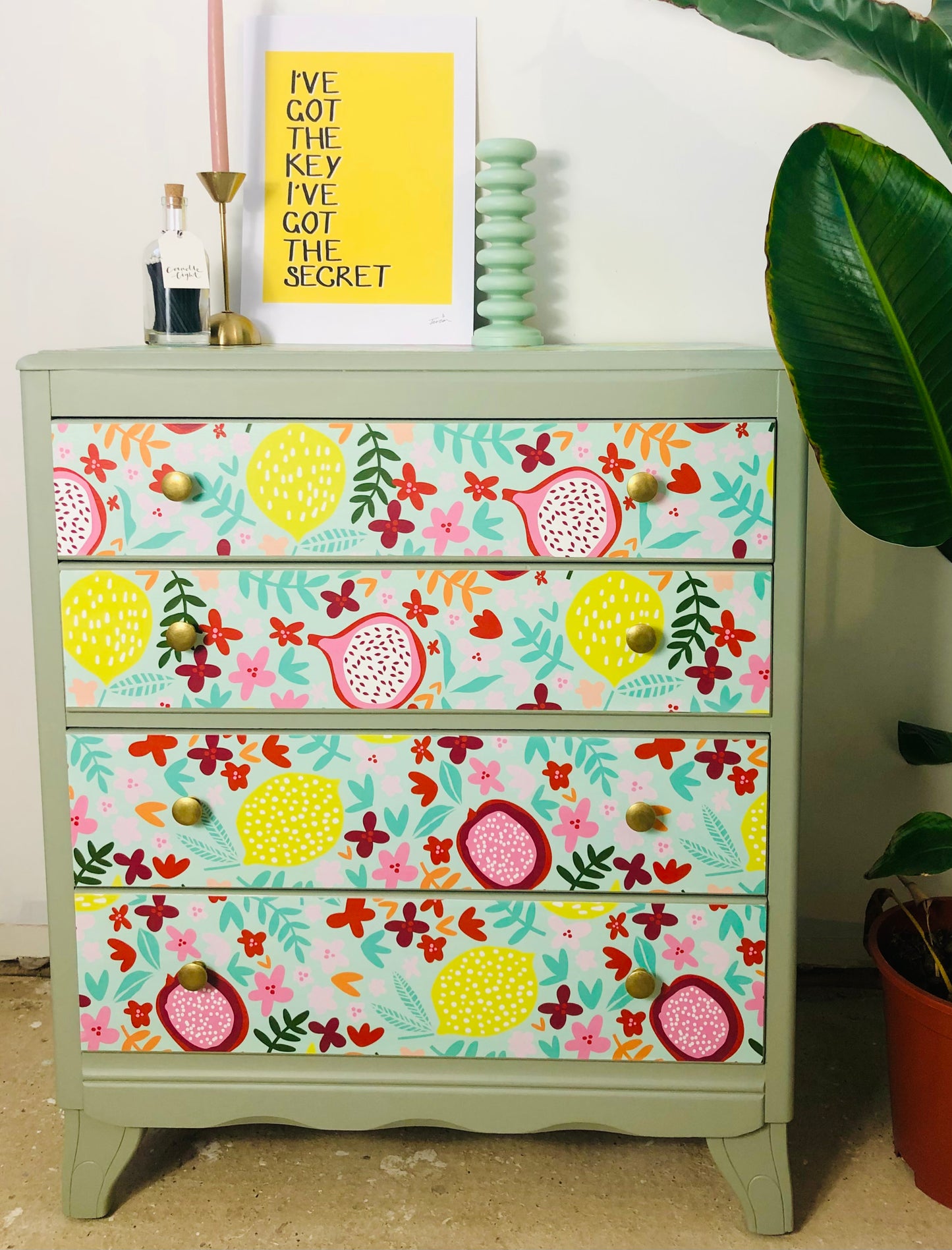 Vintage Harris Lebus chest of drawers, painted neutral green with colourful floral and fruit print wallpaper